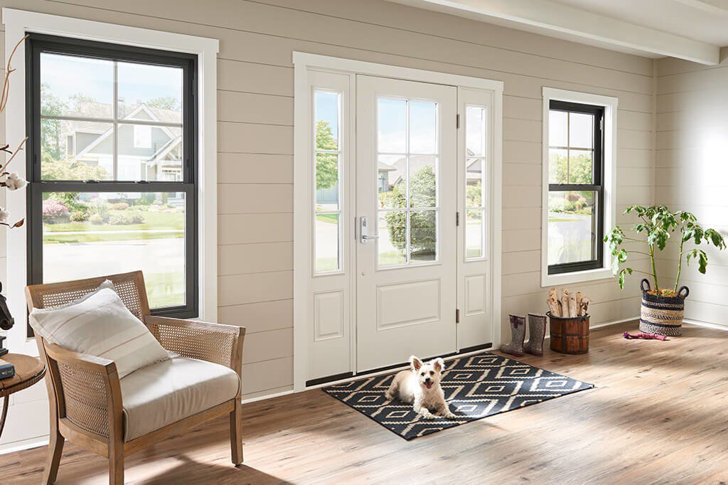 The living room and entry way of a craftsman-style home that has a dog laying on the front door mat.&nbsp;