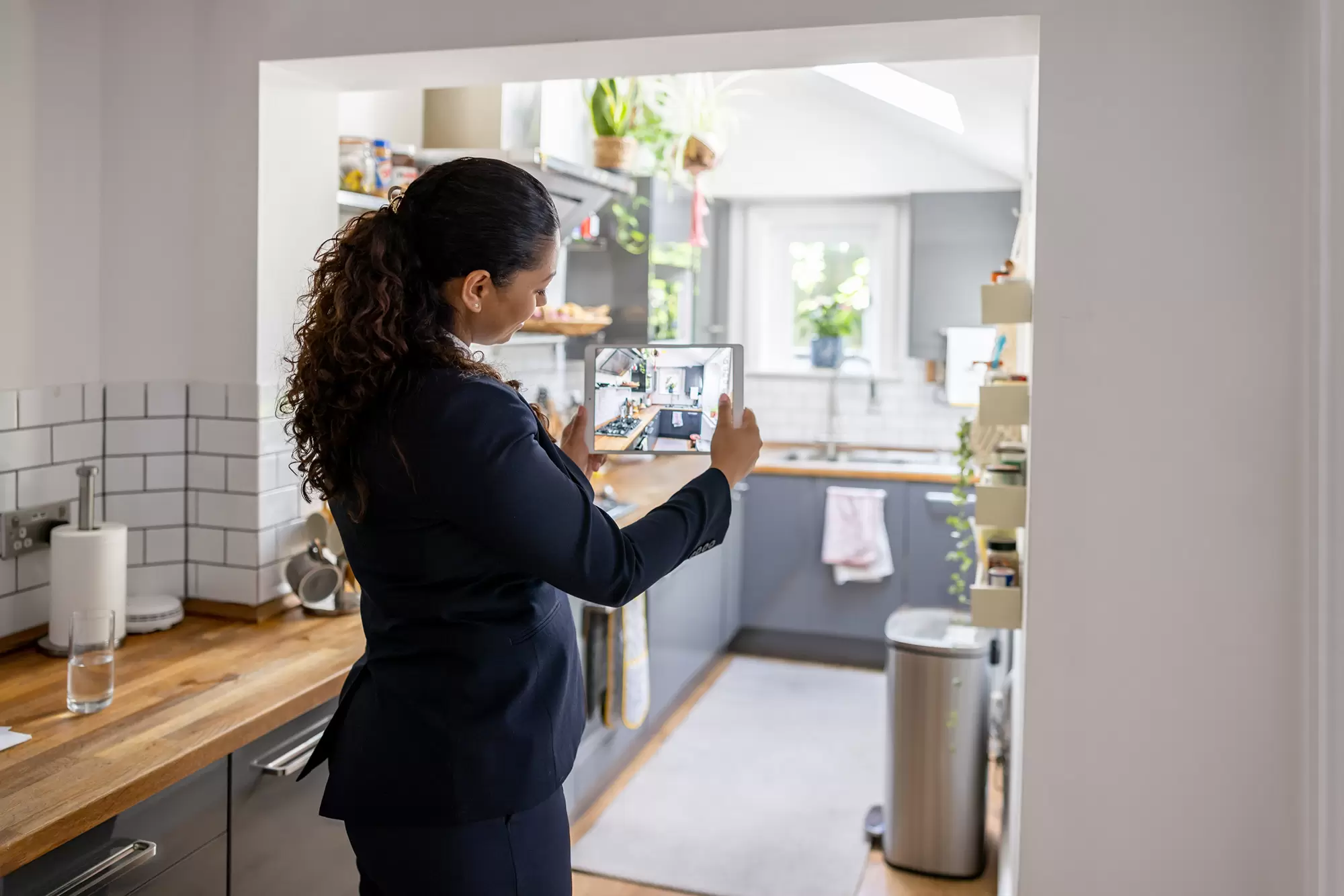 Real estate agent taking a photo of a kitchen interior with a tablet device.