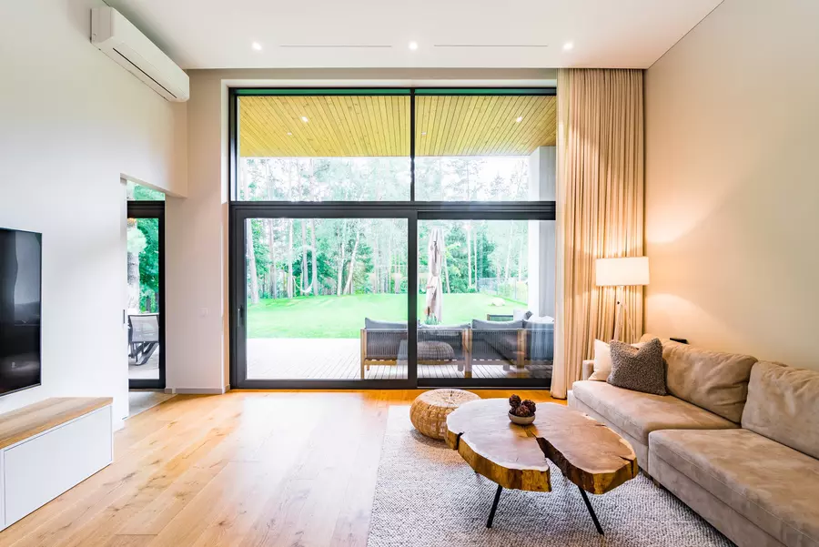 A large room in a modern home with big black-framed windows 