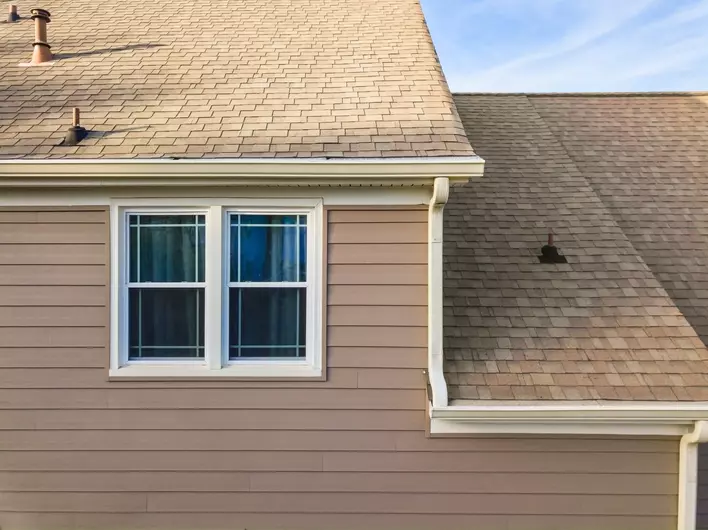 A home with insulated vinyl siding, a window on the side, and a shingled roof
