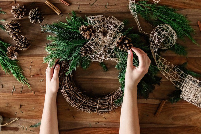 Hands making handmade bow on Christmas wreath