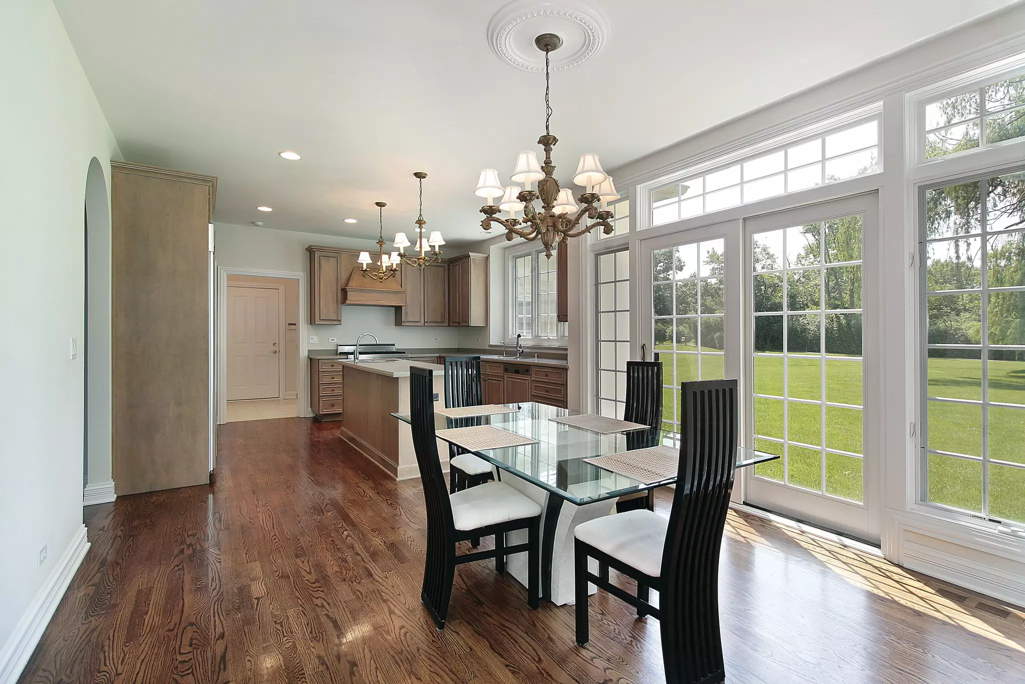 White sliding patio door shown with interior kitchen and dining room surrounded by casement windows.