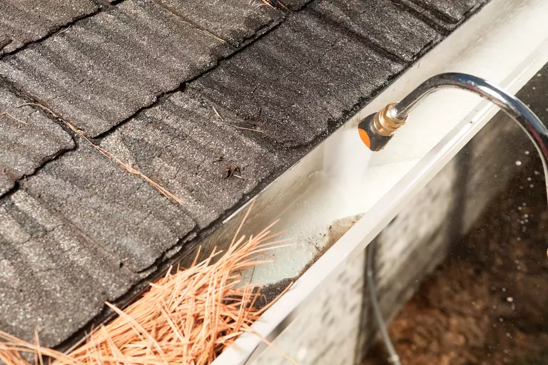 A hose connected to a home being used to flush out the pine straw and other debris from the gutters.