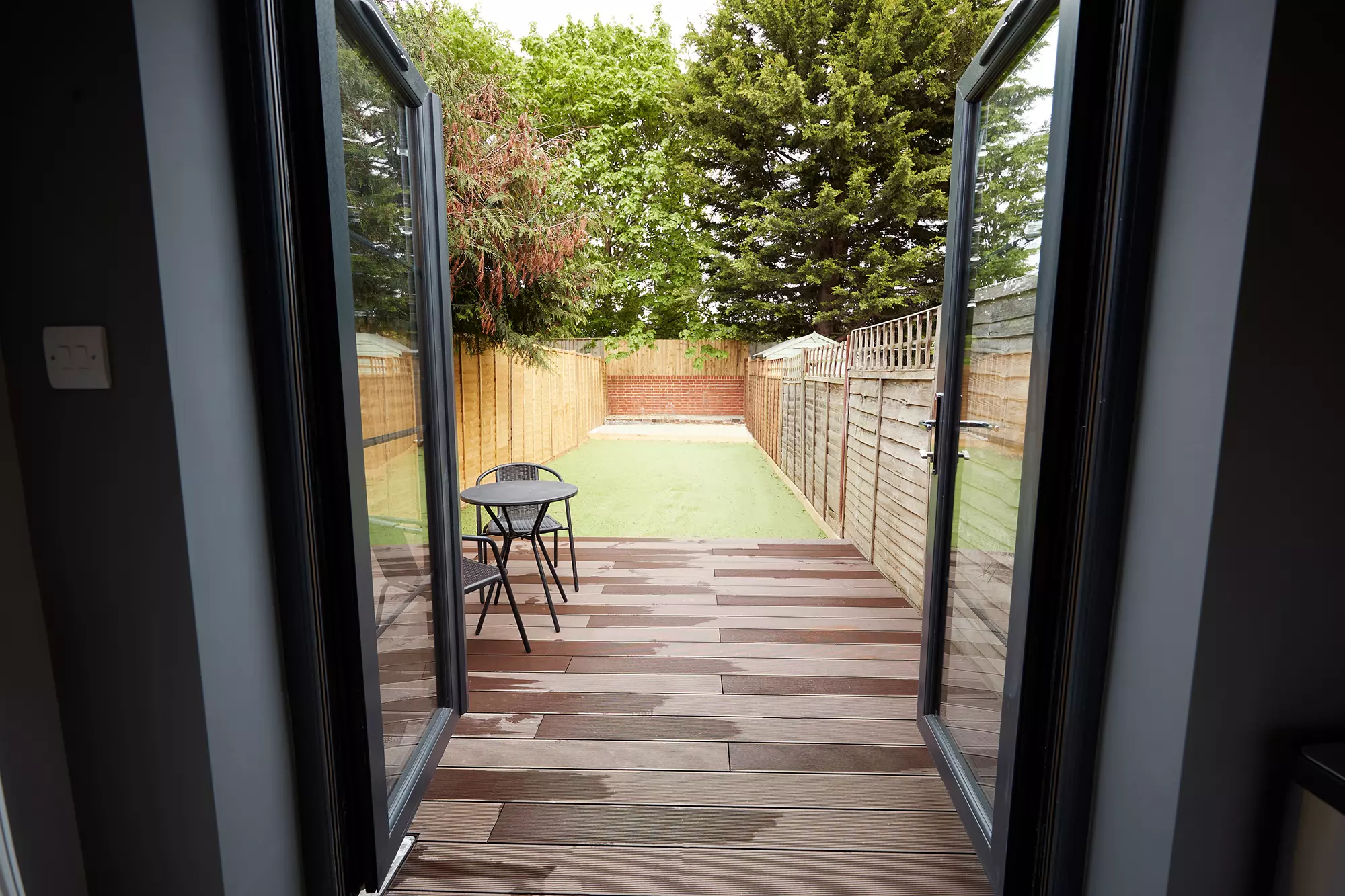 View to the garden from the back patio door of a home.