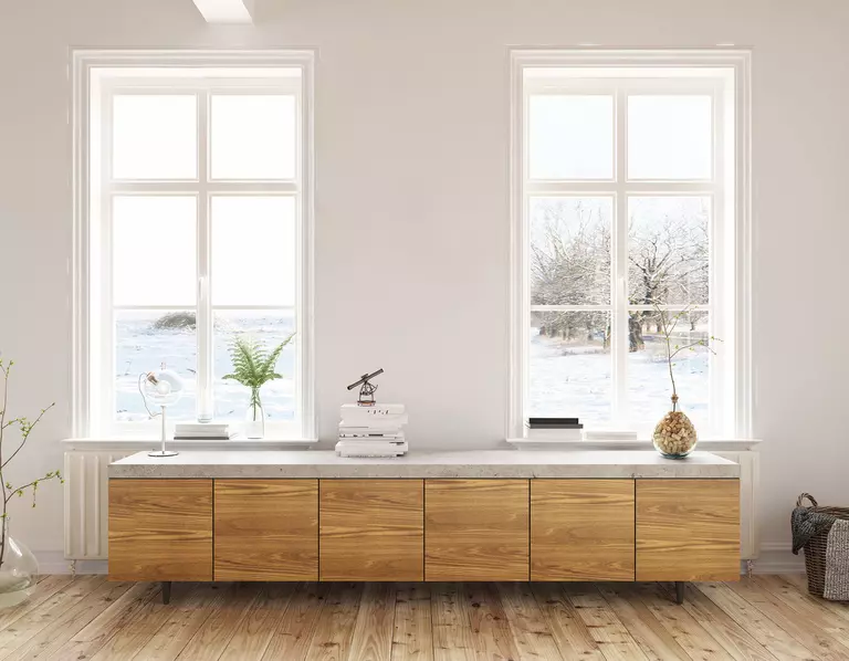 Two large windows in the office room of a home overlooking the snowy outdoors.