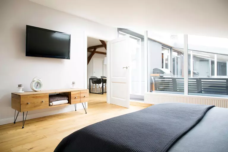 A bedroom with its door open to the hall beyond. By keeping doors open throughout your home on summer days, you can help equalize the room temperatures and make things easier on your HVAC unit.