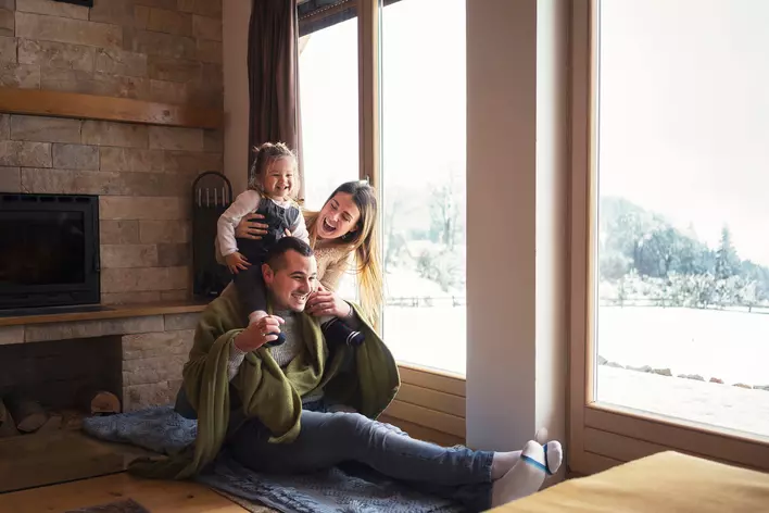Two parents and their daughter are sitting together in their cozy living room, looking
through their large picture windows at the snow outside.