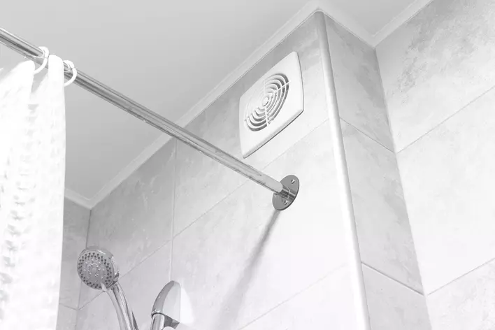 A fan above a shower curtain rod in a bathroom. Using fans and vents in humid rooms
            can help prevent condensation on the inside of windows.