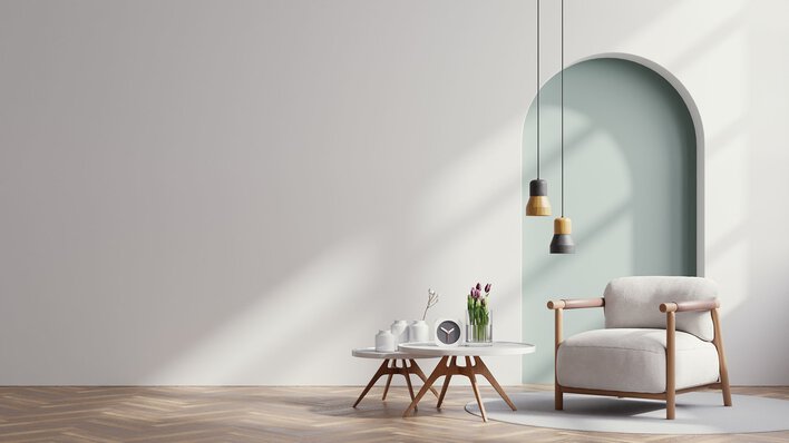A staged living space with minimalist furnishings and a wall arch indicative of modern interior design trends.