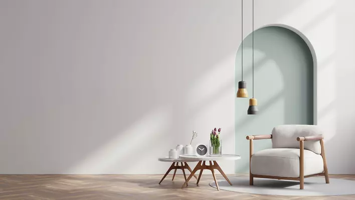 A staged living space with minimalist furnishings and a wall arch indicative of modern interior design trends.
