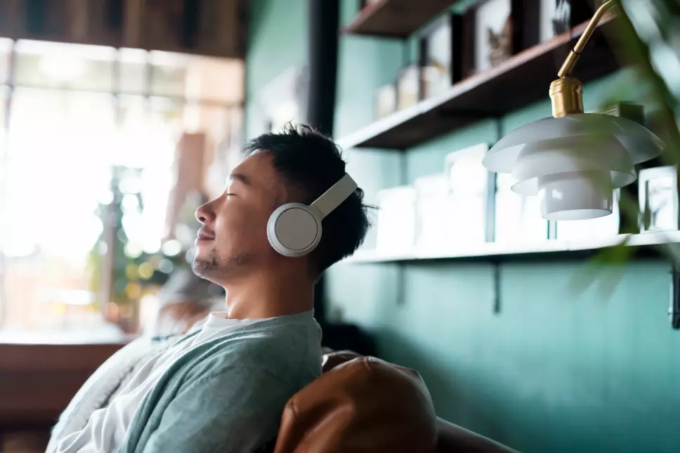 A man with his eyes closed sitting on a couch with headphones on