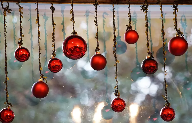 Red ornaments hanging in front of a window.