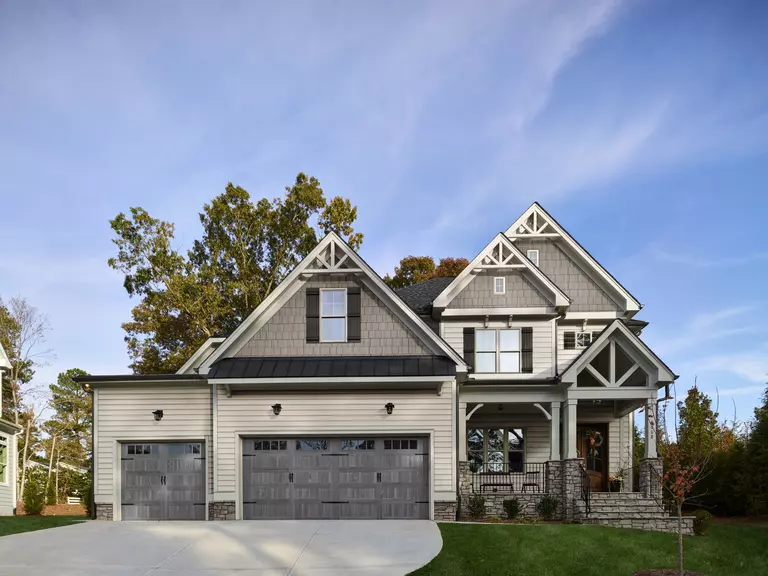 The front of a home with light gray vinyl siding and dark shakes.