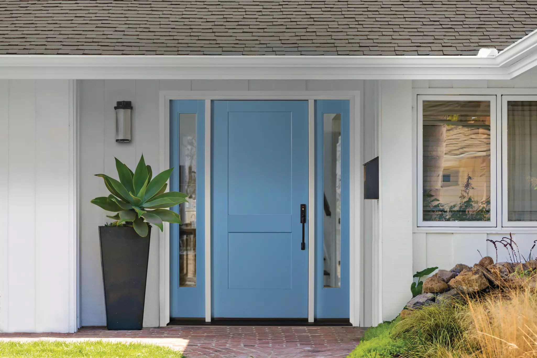 Front porch with a blue entry door with sidelites.
