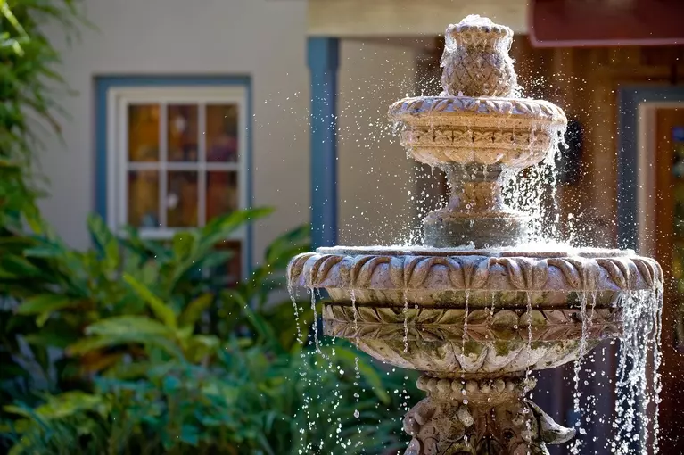 A large water fountain in the backyard of a home to add comfort and peace to the outdoor living space.