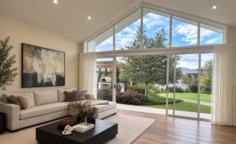 A spacious living room with bi-parting sliding patio doors that have shaped windows above
