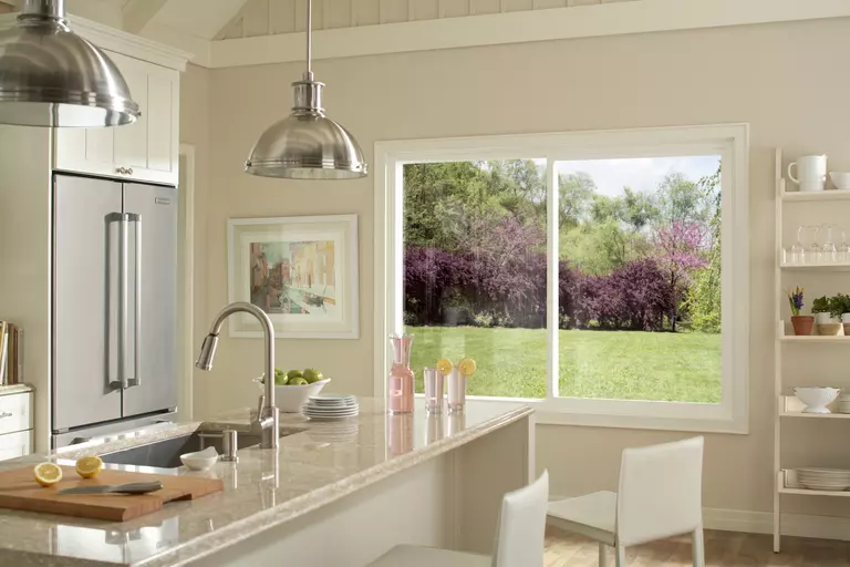 A kitchen window with a single vertical divider and a yard visible through it.