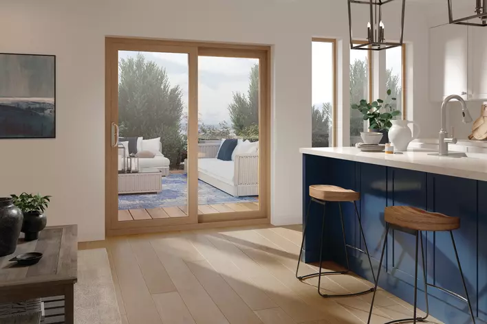 A modern, white kitchen with sliding patio doors leading to a decorated back patio with couches and rugs.