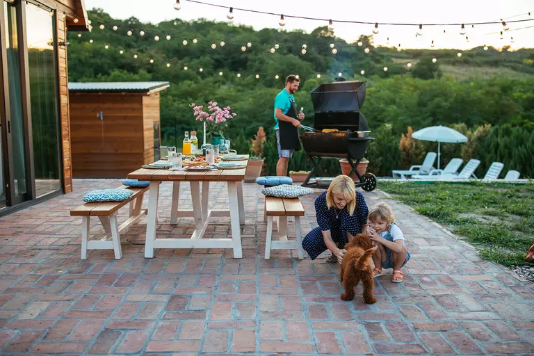 A renovated back patio with string bulb lights and outdoor dining furniture that allows for a great hosting space.