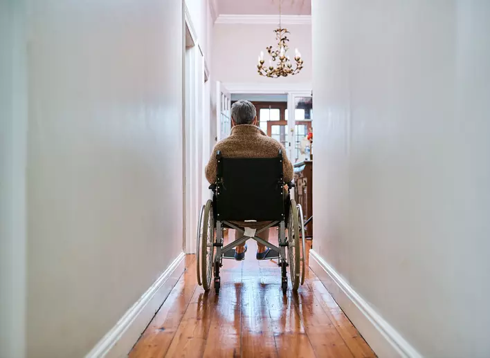 An older woman in a wheelchair going down a hallway that has been widened in her
age-in-place home.