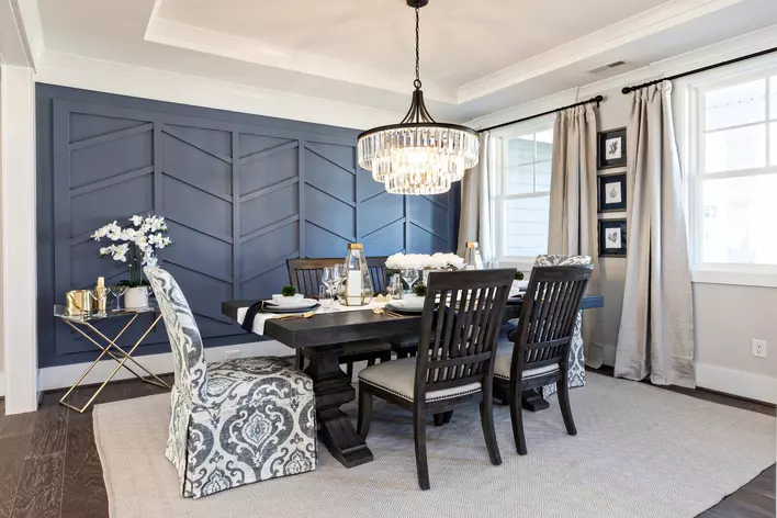 A decorated dining room table with chairs and a chandelier light fixture above it inside of a home