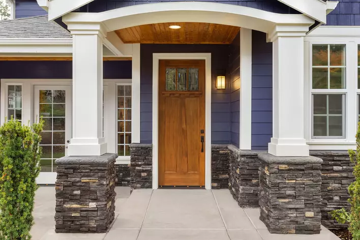 Front exterior of a blue home with a wood entry door.