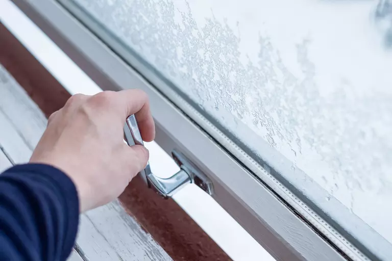 A person opening an icy awning window with the handle.