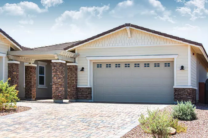 Tan short panel garage door with stockton windows installed on a residential home