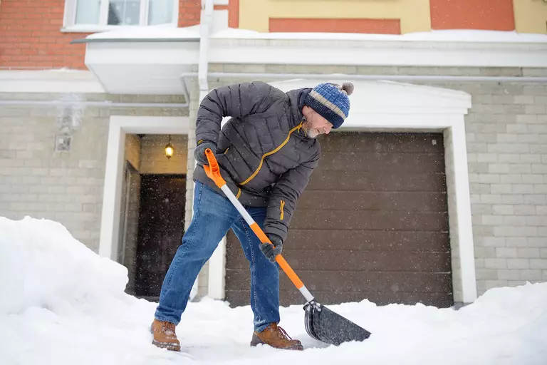A man shoveling the snow off a driveway.