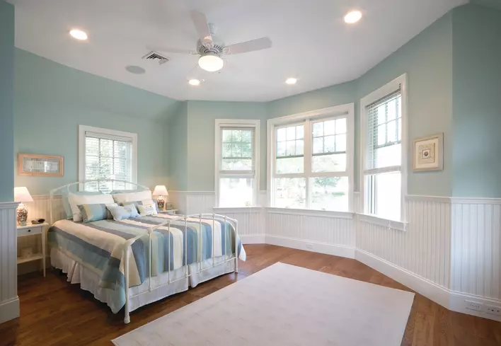 A blue-colored bedroom gets ample natural light from four Low-E windows along the exterior wall.