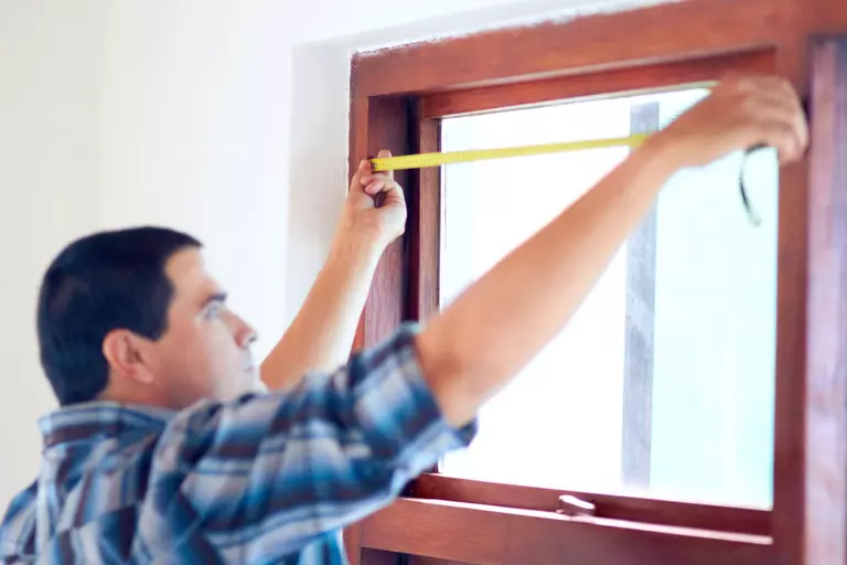 Man taking careful measurements as he prepares to install new windows and doors.