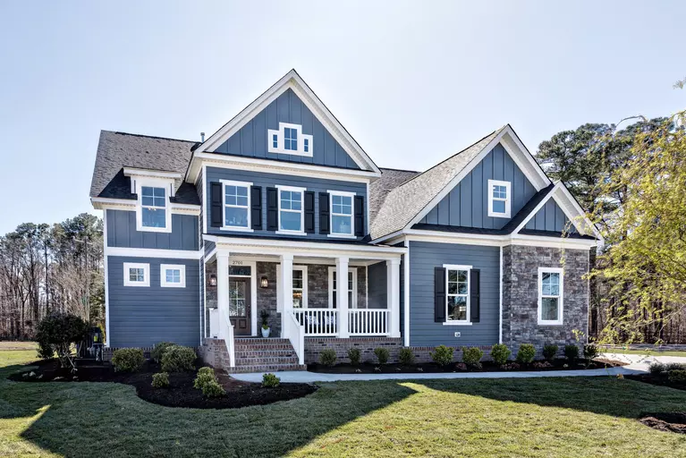 Two-story home with a dark blue exterior and multiple window styles.