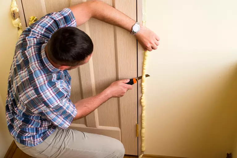 Man using polyurethane mounting foam on a door in the home.