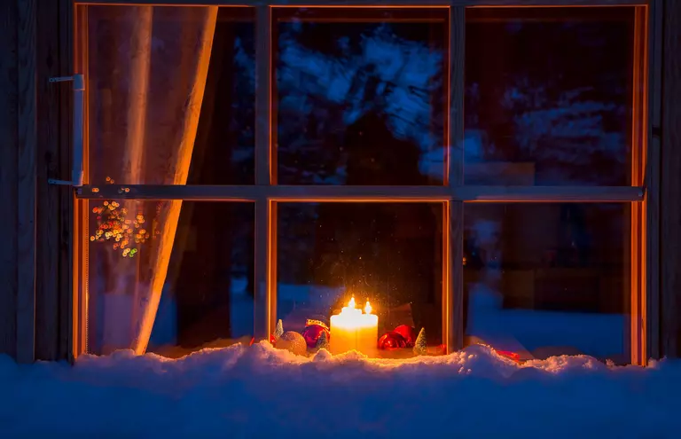 A group of holiday candles in front of a dark, snowy landscape.