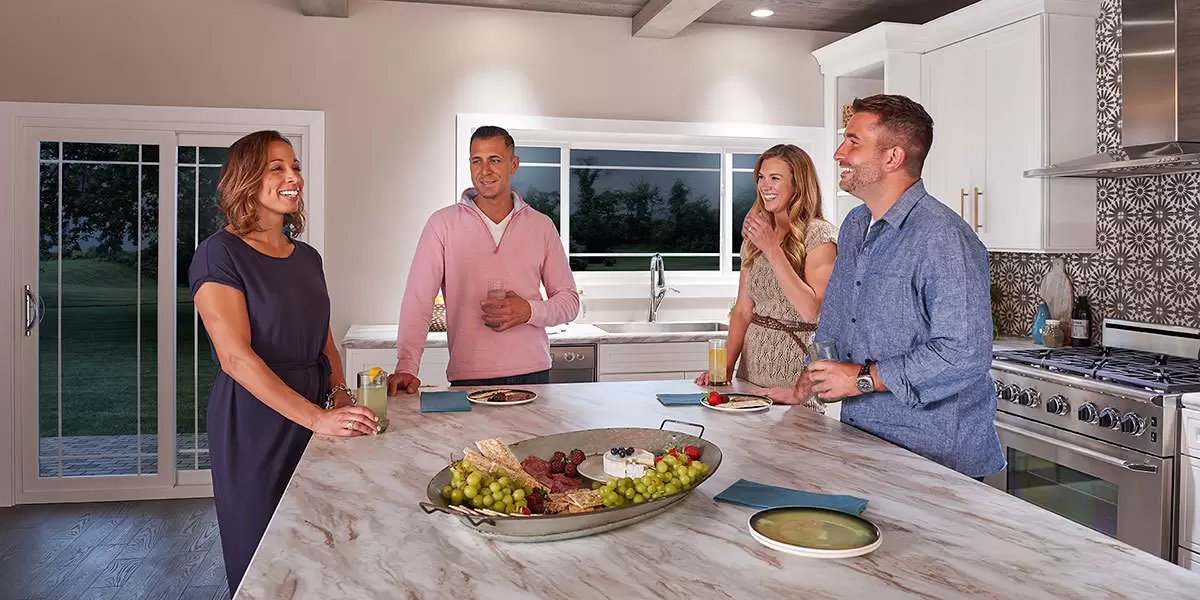 Men and women gathered around a kitchen island.