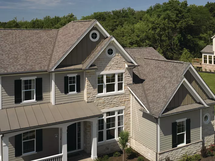 A home with a vinyl siding and stone exterior that has a new roof with asphalt-colored shingles.