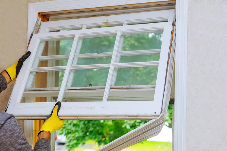 Worker removing an old window from a wall.