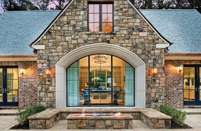 Black wood-clad direct set & radius windows behind a stone patio with a firepit