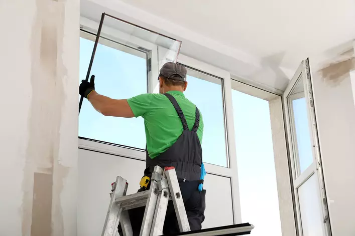 A contractor installing energy-efficient windows on a home to save money. 