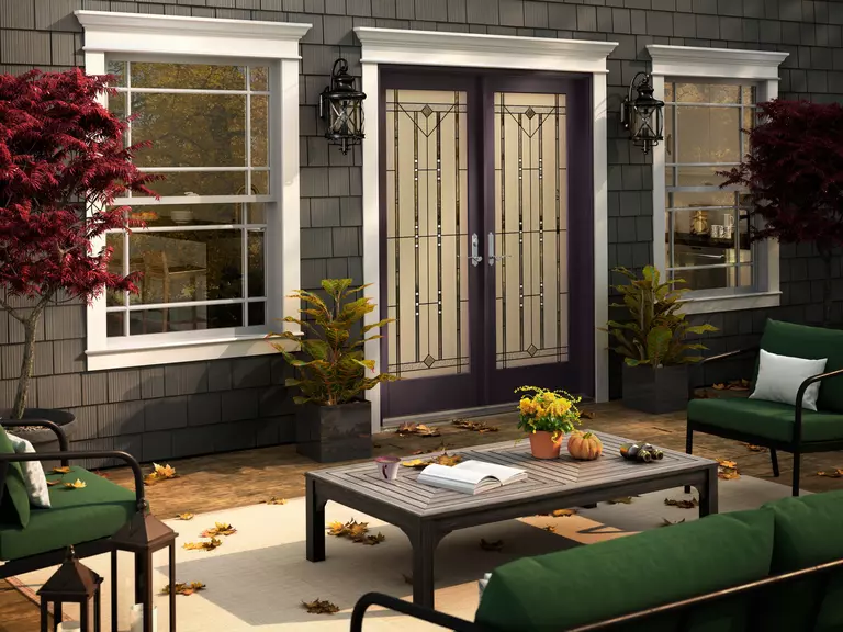 Outdoor patio of a home in autumn with white double-hung windows.