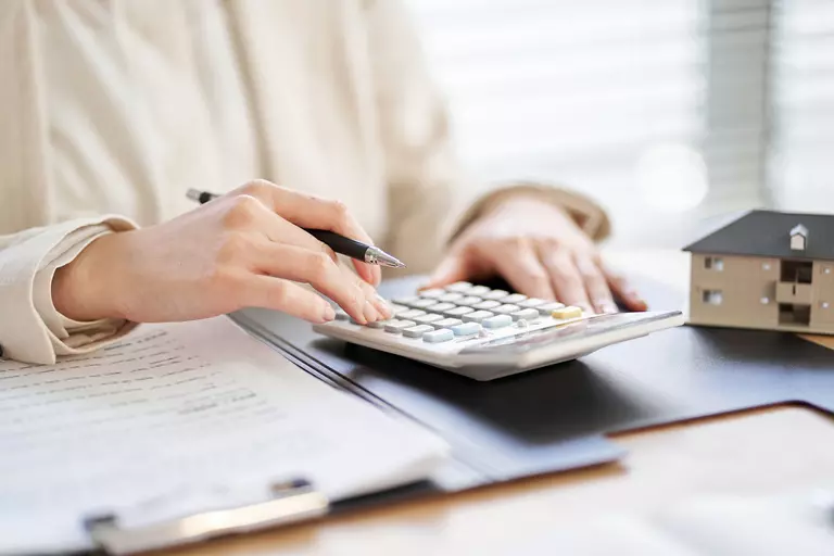 A woman calculating estimated costs of her home remodel on her calculator.