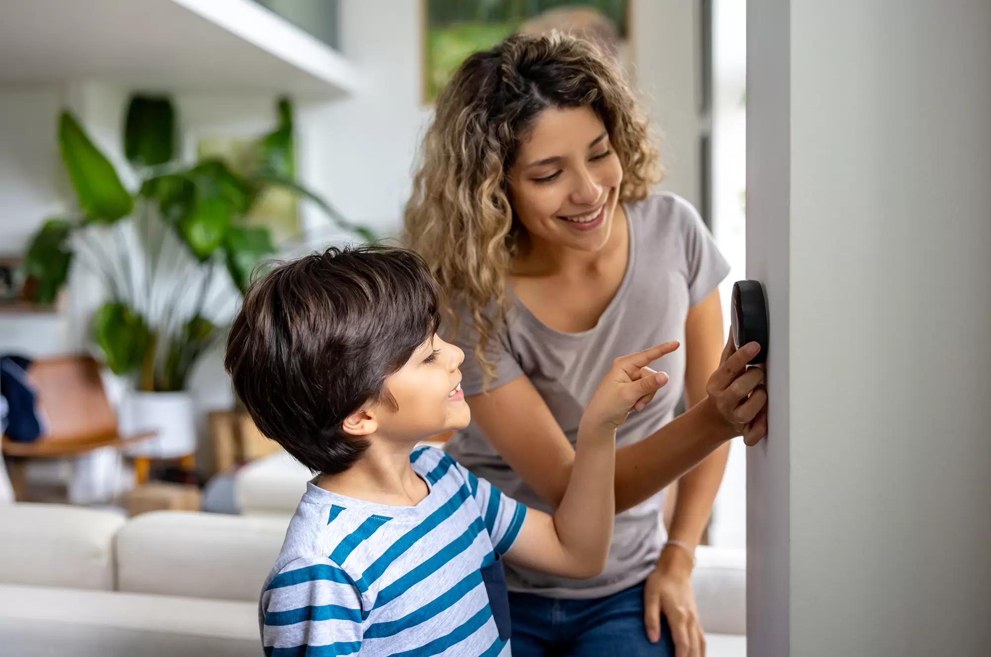 Woman and child adjusting a thermostat.