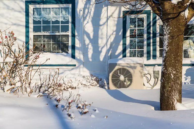 The side of a home with snow on the ground.