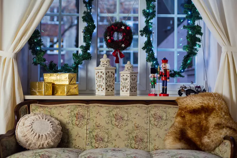 A bay window with white drapes decorated with festive items.