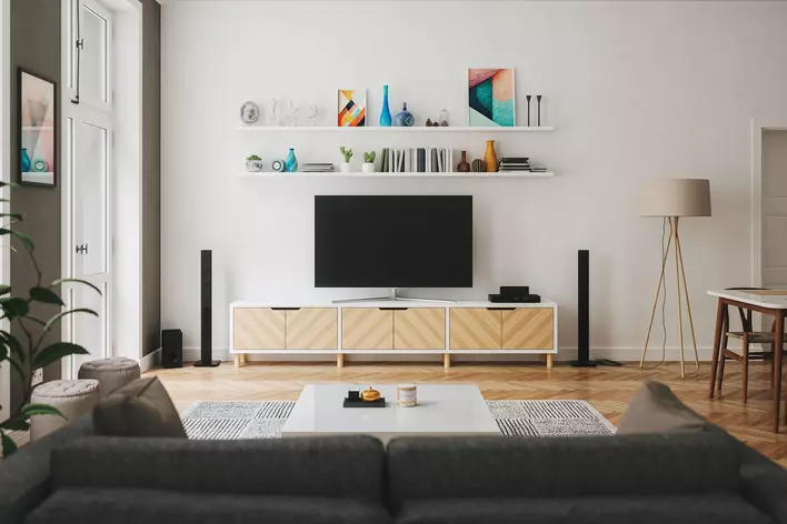 A pair of wall-mounted shelves above a flatscreen TV in a spacious living room. Various
personal items can be seen on the shelves, including paintings and vases.