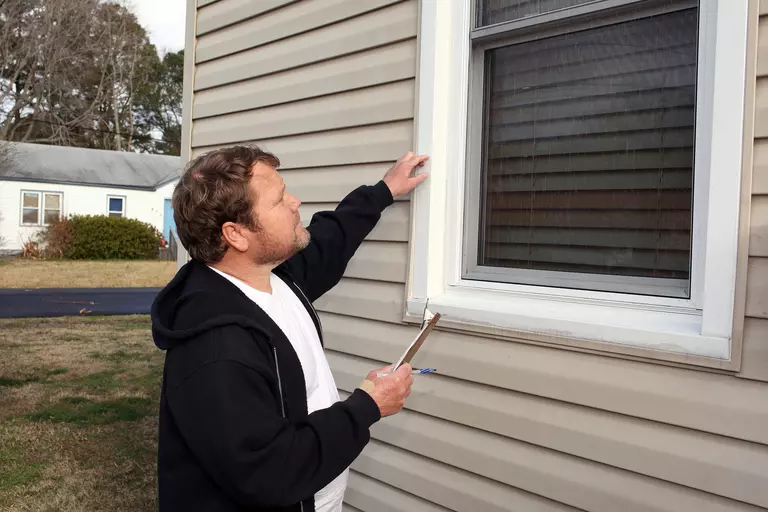 Person inspecting the windows of their home for replacement or repair.