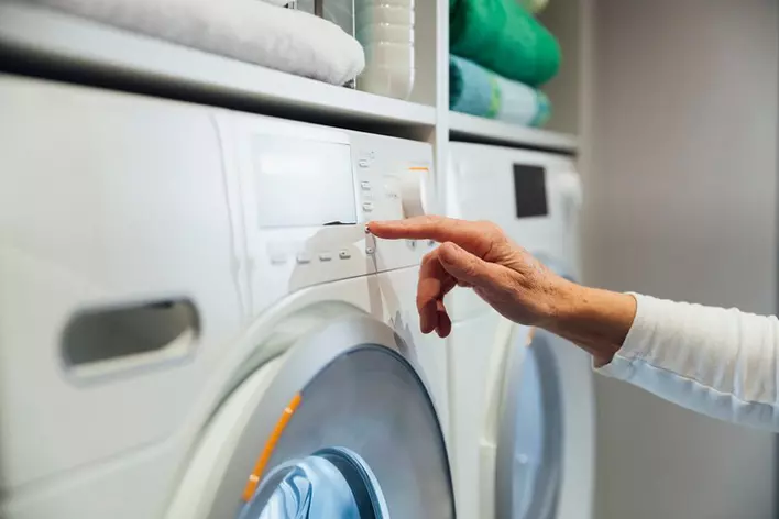 A person starting their laundry in an eco-friendly washing machine.