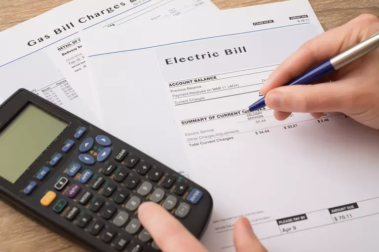 Person calculating the expenses on an electric bill