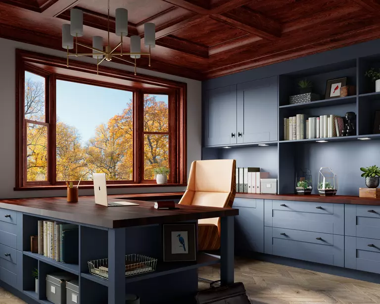Home office featuring a bay window, a blue desk, and blue cabinetry.