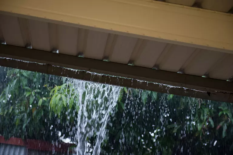 A clogged gutter overflowing during a downpour.